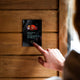 Harvia Fenix control panel surface mounted on a timber sauna wall being operated by hand