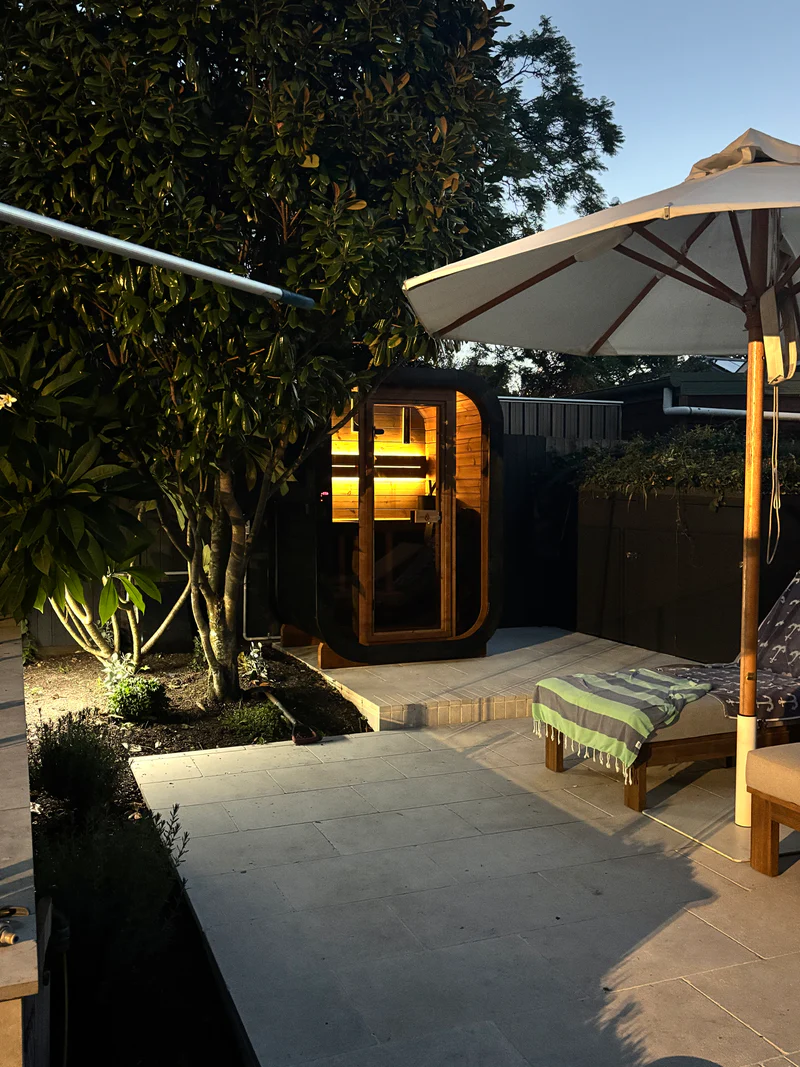 After-dark wellness setup, sauna lit, lounger waiting.