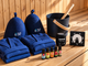 Two felt sauna hats, two folded white robes, small oil bottles and a speaker beside a wooden bucket with a ladle and a round dial, on a pale sauna bench
