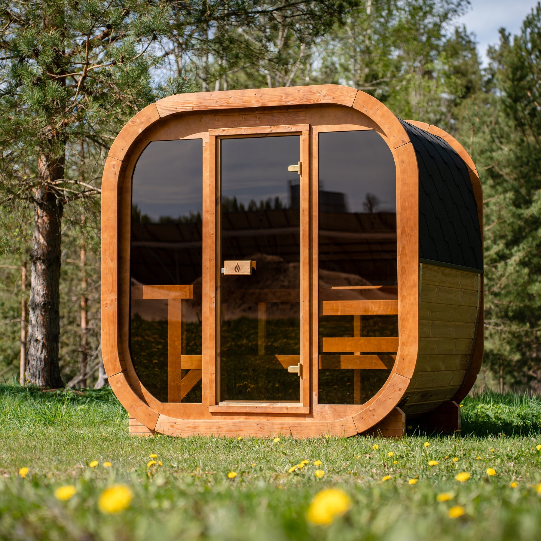 PlusLife Max Traditional 2.0 outdoor sauna cabin: rounded honey timber ring frame, tinted glass front with a central timber-framed door, charcoal shingled roof